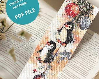 May include: A cross-stitch bookmark featuring two penguins with red feet and beaks, holding onto ornaments. The bookmark has the text "CROSS STITCH PATTERN PDF FILE" in a blue circle. The background is an open book.