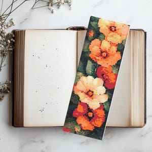 May include: A floral bookmark with a design of orange and white flowers on a dark green background.