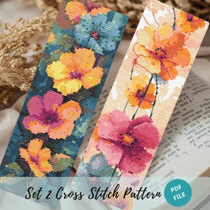 May include: Two cross stitch bookmark patterns featuring floral designs. The first bookmark pattern features a dark blue background with pink, yellow, and blue flowers. The second bookmark pattern features a white background with pink, yellow, and orange flowers. The text "Set 2 Cross Stitch Pattern PDF File" is at the bottom of the image.