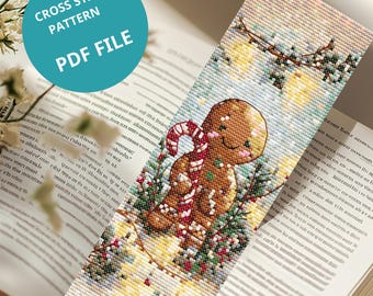 Puede incluir: Un diseño de marcapáginas de punto de cruz con un hombre de jengibre y un bastón de caramelo, sobre un fondo nevado con vegetación festiva. El marcapáginas es un archivo PDF, con el texto "CROSS STITCH PATTERN PDF FILE" en un círculo turquesa.