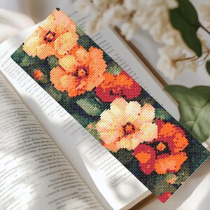 May include: A bookmark with a floral design featuring orange, yellow, and red flowers on a dark green background.