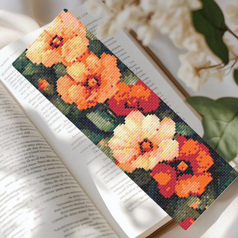 May include: A bookmark with a floral design featuring orange, yellow, and red flowers on a dark green background.