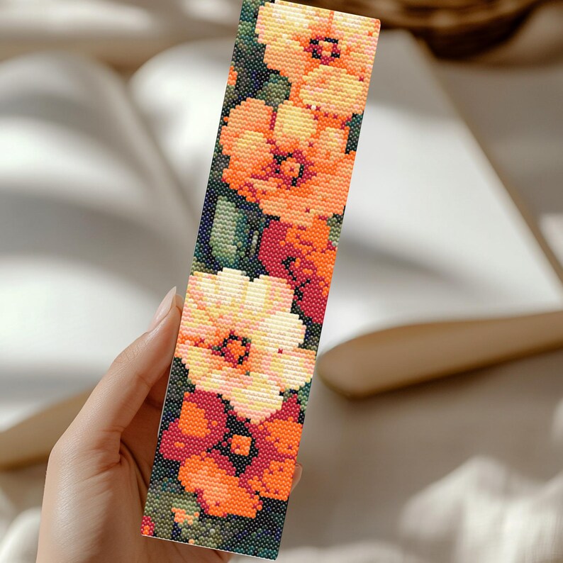 May include: A bookmark with a floral design featuring orange, yellow, and red flowers on a dark green background.