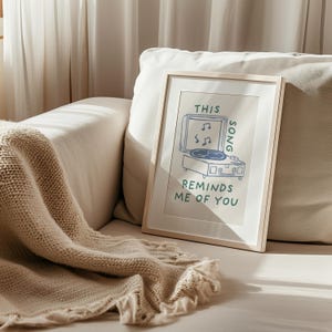 A minimalist illustration of a vintage record player with the text This song reminds me of you, placed on a neutral beige background. The design features a clean, hand-drawn aesthetic with simple, modern lines.