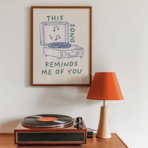 A minimalist illustration of a vintage record player with the text This song reminds me of you, placed on a neutral beige background. The design features a clean, hand-drawn aesthetic with simple, modern lines.