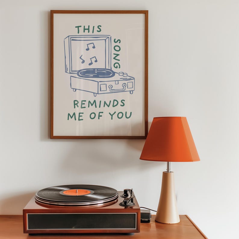 A minimalist illustration of a vintage record player with the text This song reminds me of you, placed on a neutral beige background. The design features a clean, hand-drawn aesthetic with simple, modern lines.
