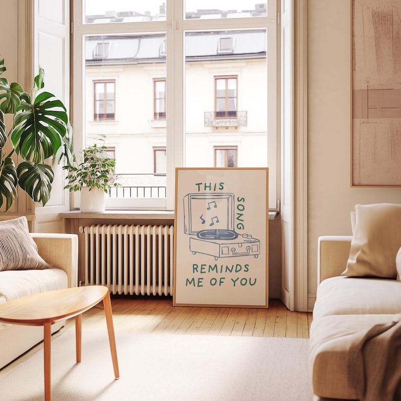 A minimalist illustration of a vintage record player with the text This song reminds me of you, placed on a neutral beige background. The design features a clean, hand-drawn aesthetic with simple, modern lines.