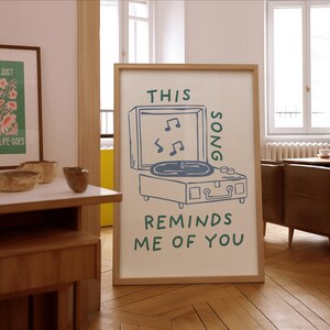 A minimalist illustration of a vintage record player with the text This song reminds me of you, placed on a neutral beige background. The design features a clean, hand-drawn aesthetic with simple, modern lines.