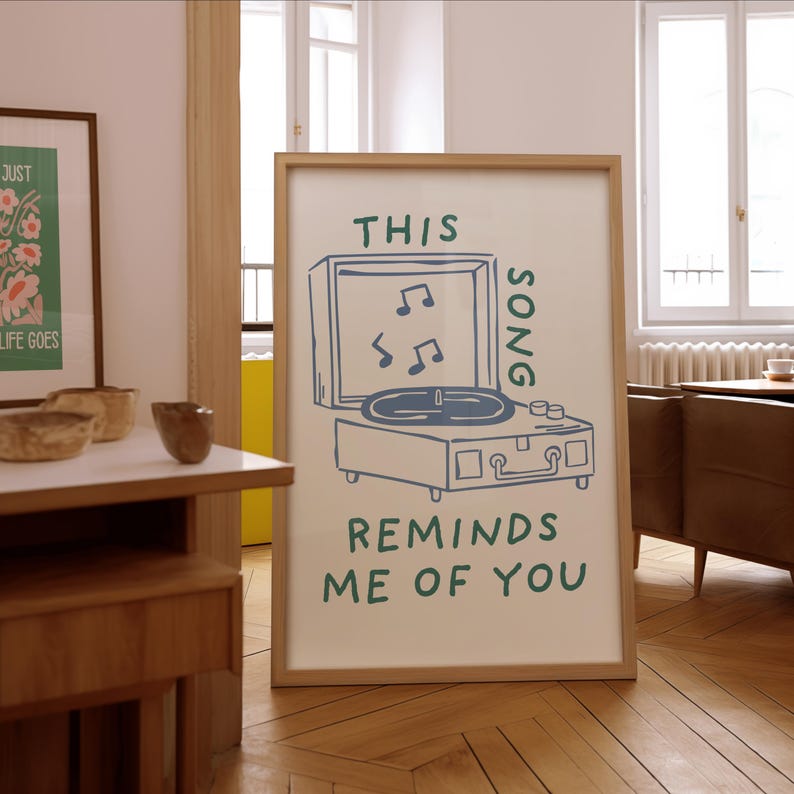 A minimalist illustration of a vintage record player with the text This song reminds me of you, placed on a neutral beige background. The design features a clean, hand-drawn aesthetic with simple, modern lines.