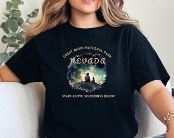 Op de afbeelding: Zwart T-shirt met een afbeelding van Great Basin National Park in Nevada. Het ontwerp bevat de tekst "Nevada" en "Stars Above, Wilderness Below" met een silhouet van twee figuren. Het shirt heeft een ronde hals.
