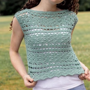 May include: A seafoam green crochet top with a scoop neckline and cap sleeves. The top features a detailed openwork pattern and a scalloped hemline. The garment is worn over a white undershirt.