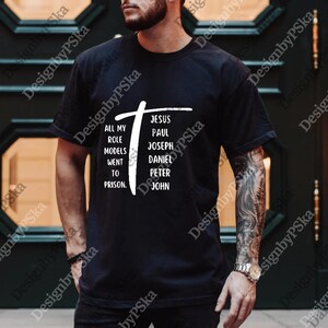 May include: Black t-shirt with a white cross graphic and the text "ALL MY ROLE MODELS WENT TO PRISON. JESUS PAUL JOSEPH DANIEL PETER JOHN."