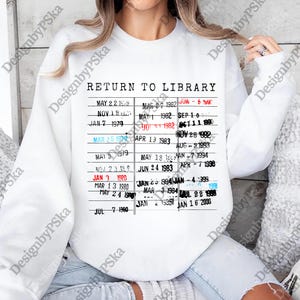 May include: White sweatshirt featuring a vintage library card design. The graphic includes the text "RETURN TO LIBRARY" above a list of dates. The dates are printed in black and red, creating a retro aesthetic.