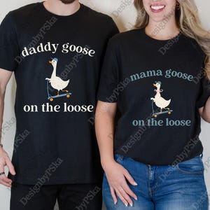 May include: Black t-shirts with matching designs. One shirt says "daddy goose on the loose" with a goose on a scooter. The other shirt says "mama goose on the loose" with a goose on a scooter. Both shirts have a cartoon goose wearing a hat.