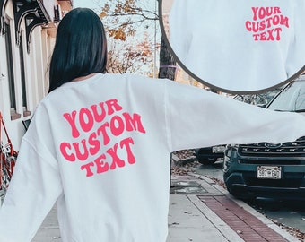 May include: White sweatshirt with pink text that says "YOUR CUSTOM TEXT" in a retro font.