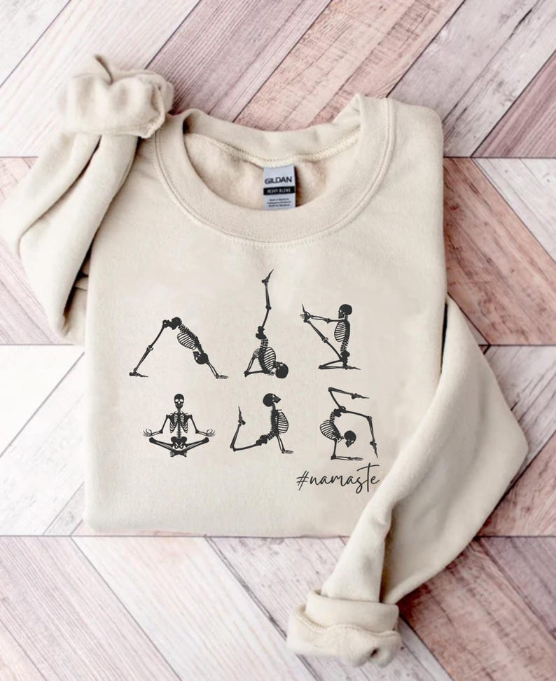 May include: A beige sweatshirt with a graphic of skeletons doing yoga poses. The text "#namaste" is printed below the skeletons.