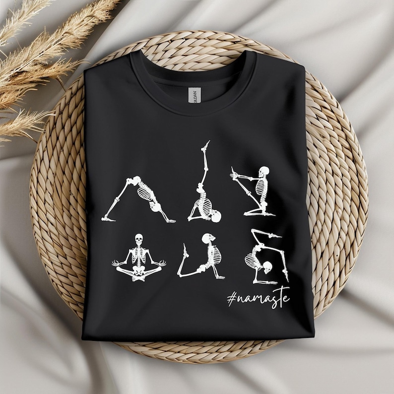 May include: Black t-shirt with a white graphic of skeletons doing yoga poses. The text "#namaste" is below the skeletons.