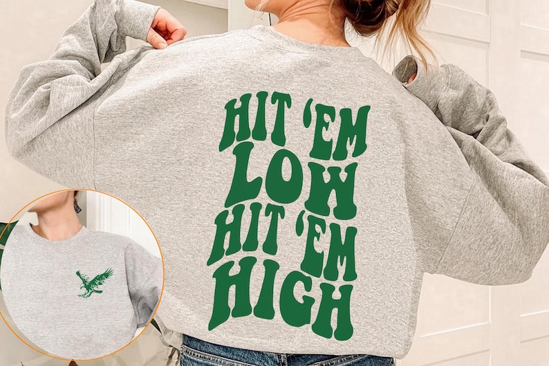 K&ouml;nnte beinhalten: Grauer Pullover mit gr&uuml;ner Grafik, auf dem "Hit 'em Low Hit 'em High" steht.