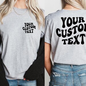 May include: A gray t-shirt with "YOUR CUSTOM TEXT" printed in black on the front and back. The text is in a retro, bubble-like font.