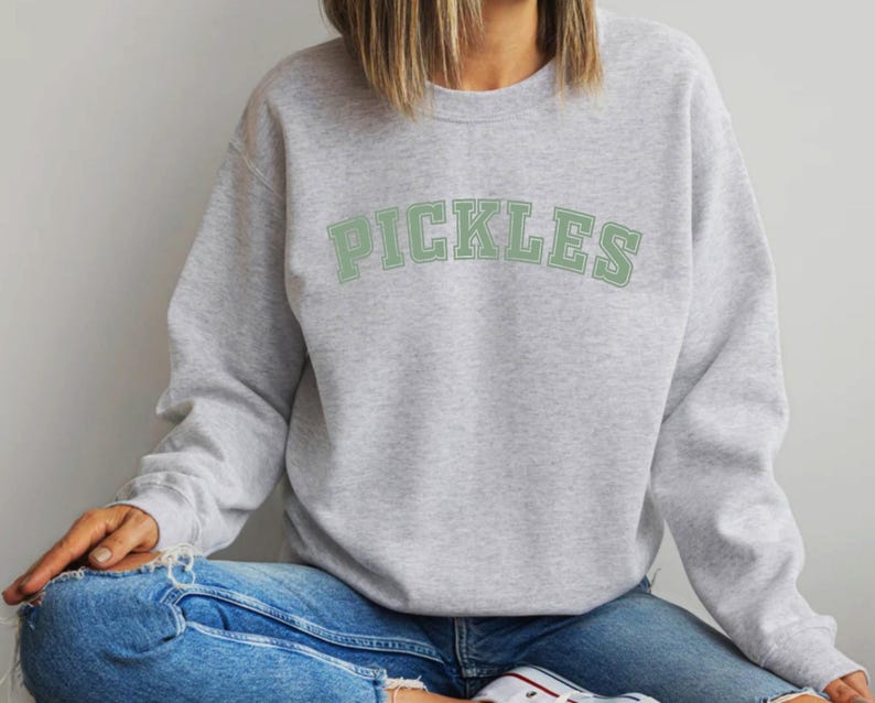 May include: A gray sweatshirt with the word "PICKLES" printed in green on the front.