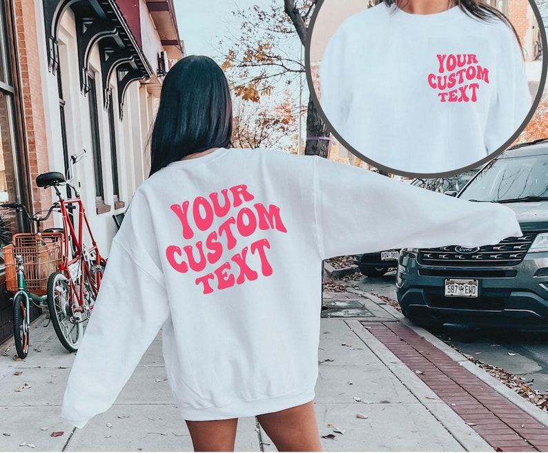 May include: White sweatshirt with pink text that says "YOUR CUSTOM TEXT" in a retro font.