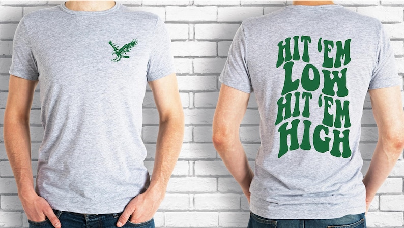 K&ouml;nnte beinhalten: Ein hellgraues T-Shirt mit einem gr&uuml;nen Vogelmotiv auf der Vorderseite und dem Text "Hit 'em Low Hit 'em High" in Gr&uuml;n auf der R&uuml;ckseite.
