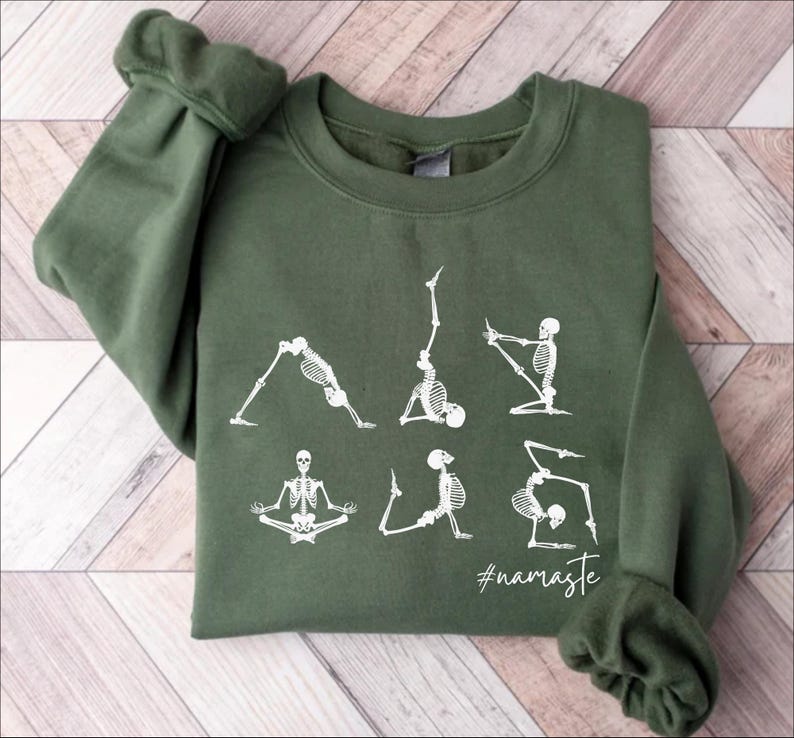 May include: A green sweatshirt with a white graphic of skeletons doing yoga poses. The text "#namaste" is printed below the skeletons.