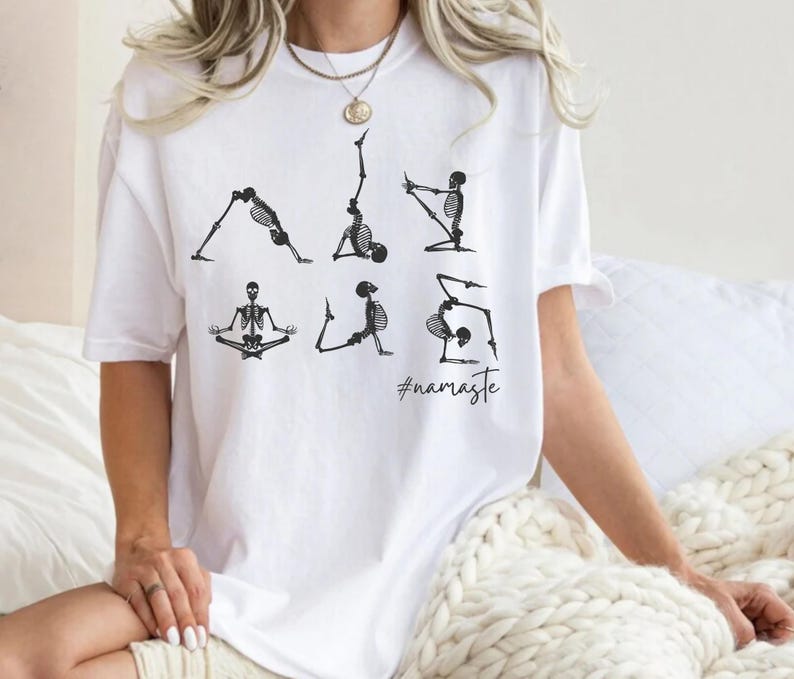 May include: White t-shirt with a graphic of skeletons doing yoga poses. The text "#namaste" is printed below the skeletons.