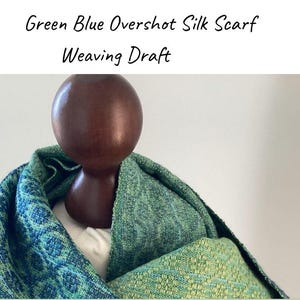 Puede incluir: Una bufanda de seda verde y azul drapeada sobre una forma de madera. La bufanda presenta un patrón tejido en tonos turquesa y verde. El texto en la parte superior dice "Green Blue Overshot Silk Scarf Weaving Draft."