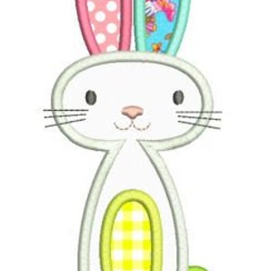 Könnte beinhalten: Ein weißer Hase mit rosa und blauen Ohren, einem gelben und weißen karierten Bauch und einem grünen Knopf-Schwanz. Der Hase ist ein einfaches Design im Cartoon-Stil.