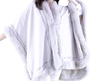 May include: A cream-colored cape with a faux fur trim. The cape has a soft, draped appearance and is trimmed with a light gray faux fur along the edges and neckline. The cape is a stylish outerwear option.