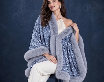 May include: A blue sequined wrap featuring a thick, plush grey faux fur trim along the edges. The garment is draped over a cream-colored sleeveless top and paired with cream-colored trousers, creating a layered look with textured fabric.