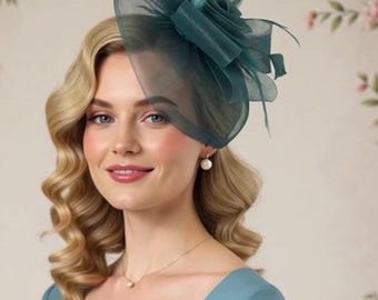 Puede incluir: Un fascinador de color verde azulado con un diseño en forma de rosa y detalles de tela transparente. La pieza para la cabeza la lleva una persona con cabello rubio y un vestido azul. El fondo presenta un estampado floral.