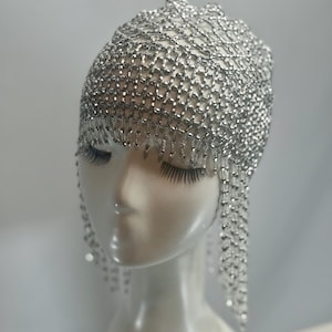 May include: A silver beaded headpiece with a chainmail design and dangling strands of beads.