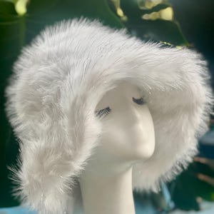 Op de afbeelding: Een witte bucket hat van nep bont met een brede rand en een pluche textuur.