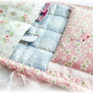 May include: A quilted fabric storage pouch with three pockets and a padded section. The pouch is decorated with floral patterns in pink, blue, and white.