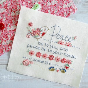 Puede incluir: Tela blanca bordada con un pájaro rojo y un diseño floral. El texto dice "Paz sea contigo, y paz sea con tu casa. 1 Samuel 25:6".