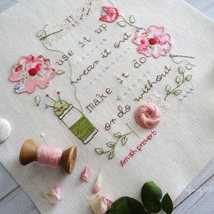 May include: White fabric embroidered with a pink and green floral design and the text "use it up wear it out make it do or do without Amish proverb".
