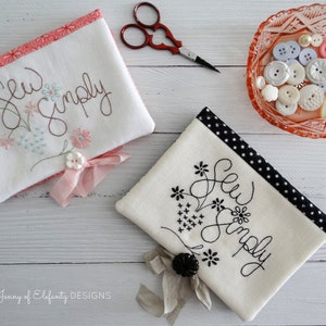 May include: Two white fabric pouches with black and pink trim. Both pouches have the text "Sew Simply" embroidered on them with floral designs. The pouch on the left has pink trim and pink flowers. The pouch on the right has black and white polka dot trim and black flowers.