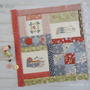 Könnte beinhalten: Ein Patchwork-Quiltblock in Rot-, Weiß- und Blautönen. Der Block besteht aus verschiedenen Quadraten und Rechtecken und zeigt eine Vielzahl von floralen und geometrischen Mustern. Der Block trägt den Titel "simple days" und "block seven".