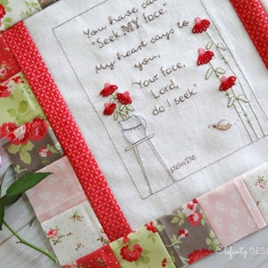 May include: A white fabric square with a red, pink, and green patchwork border. The center of the fabric square features an embroidered design of a vase with flowers and the text "You have said "Seek MY face." My heart says to you, "Your face, Lord, do I seek." Psalm 27:8"