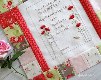 May include: A white fabric square with a red, pink, and green patchwork border. The center of the fabric square features an embroidered design of a vase with flowers and the text "You have said "Seek MY face." My heart says to you, "Your face, Lord, do I seek." Psalm 27:8"