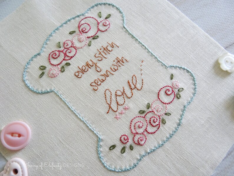 Peut inclure: Tissu brod&eacute; en forme de bobine avec le texte "every stitch sewn with love" en fil brun. La bobine est d&eacute;cor&eacute;e de roses roses et rouges et de feuilles vertes.