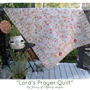 May include: A white and pink floral quilt with the words "Lord's Prayer Quilt" by Jenny of Elefantz designs printed on the bottom.