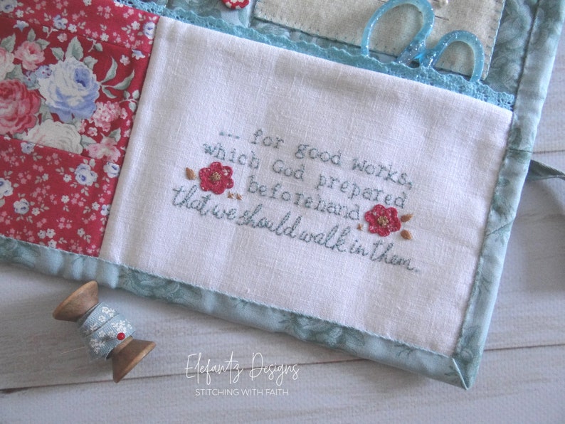 May include: A white fabric pouch with a blue border and a quote embroidered in blue thread: "...for good works, which God prepared beforehand that we should walk in them." The pouch is decorated with a floral pattern and has a small wooden spool of thread next to it.