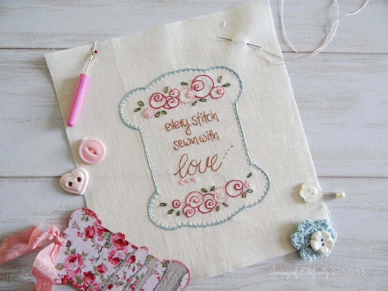 Peut inclure: Un tissu blanc avec un motif brod&eacute; bleu et vert repr&eacute;sentant une bobine de fil avec le texte "every stitch sewn with love".