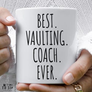 May include: White ceramic coffee mug with black text that reads "Best. Vaulting. Coach. Ever."