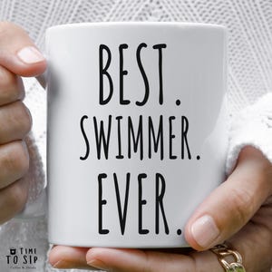 Peut inclure: Mug en céramique blanche avec du texte noir qui dit "BEST. SWIMMER. EVER."