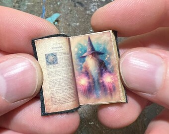 May include: Miniature open book with black binding. The right page features a colorful illustration of a wizard with a long white beard, wearing a blue hat, and holding glowing orbs. The left page has printed text and a circular design.