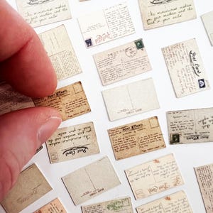 May include: Miniature vintage postcards with handwritten messages and stamps. The postcards are in various shades of brown and beige, with the words "Post Card" visible on several. A finger is holding one of the postcards.